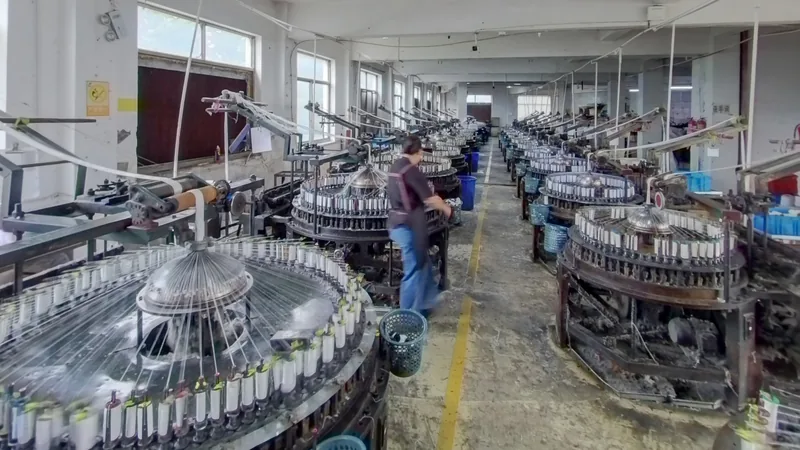 The YiTuo production floor Rows of lace knitting machines and a worker on the YiTuo production floor.